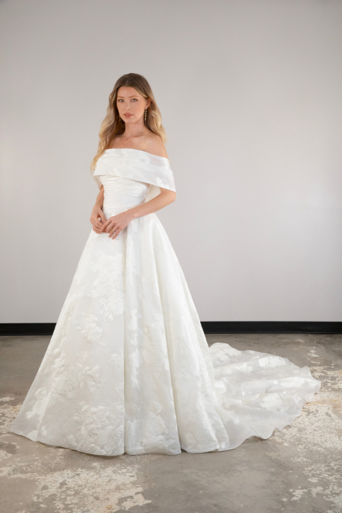 model is wearing an off the shoulder ball gown wedding dress