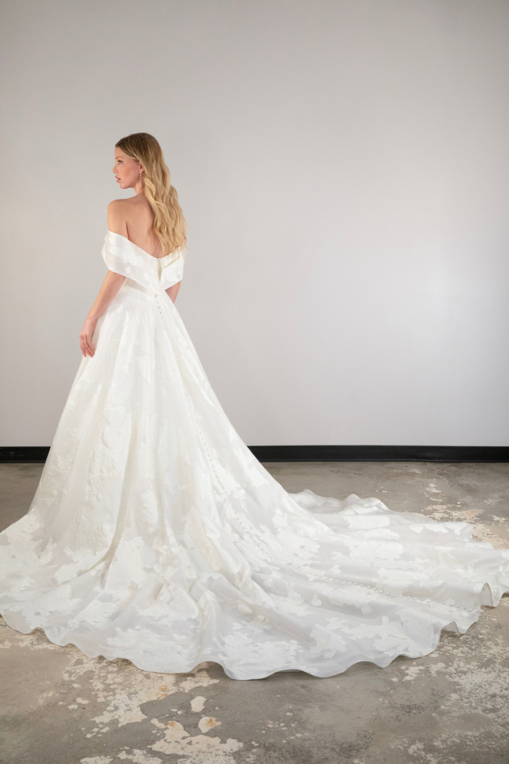 model is wearing an off the shoulder ball gown wedding dress