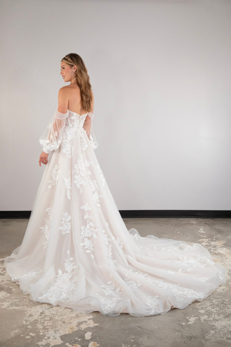 model is wearing an off the shoulder wedding dress with a long train