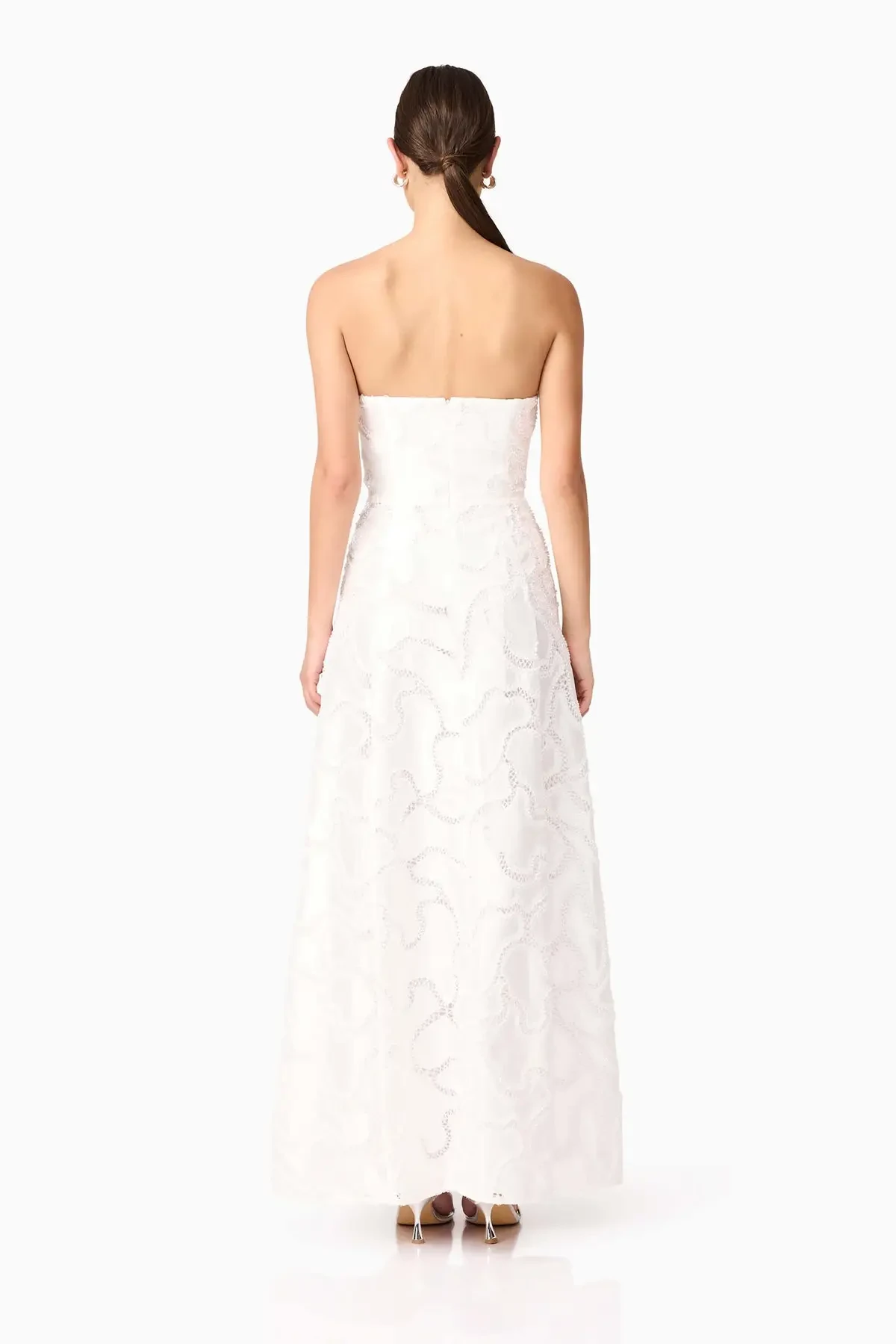 Model is wearing a strapless white gown in beaded sateen fabric that shimmers subtly, finished with a timeless fit-and-flare silhouette.