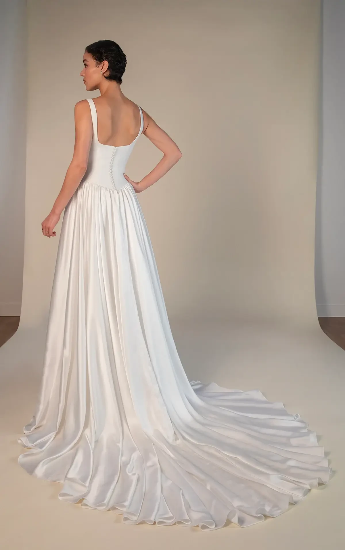 Model is wearing a sleek A-line gown with a square neckline, delicate straps, and a softly gathered skirt that flows gracefully.