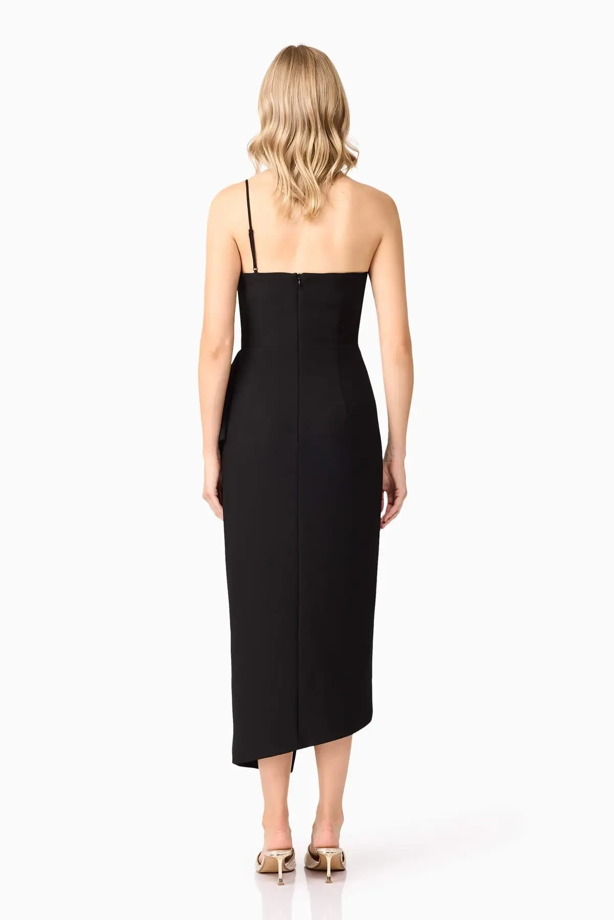 Model is wearing a sleek black midi dress with a frill high neckline, asymmetrical hemline, and a body-contouring fit that transitions effortlessly from dinner to the dance floor.